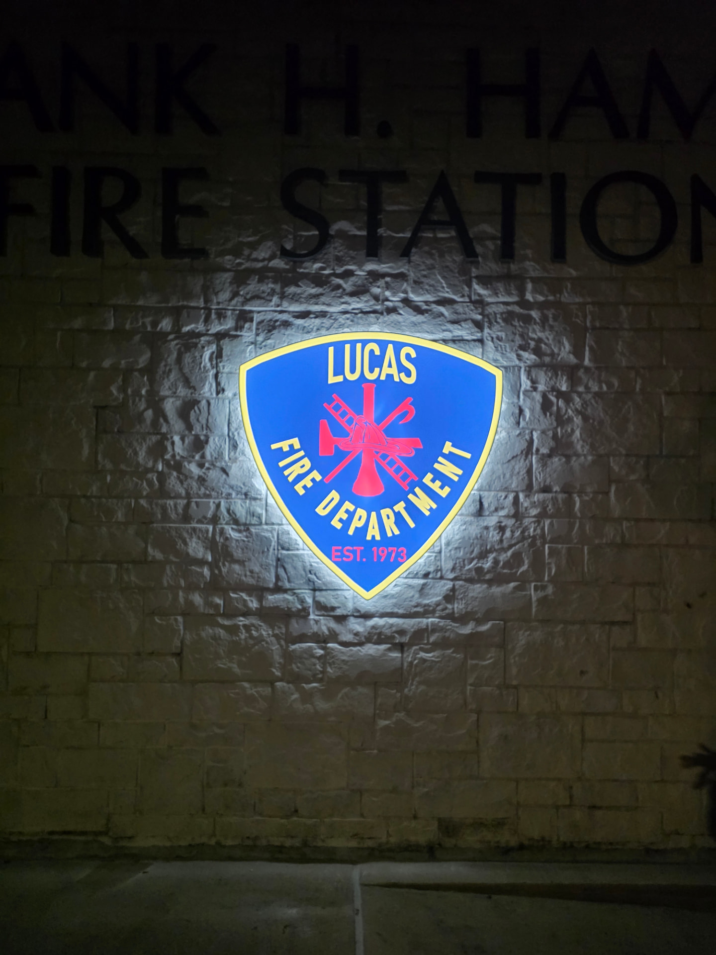 Illuminated Lucas Fire Department exterior shield sign at night, powered by electrical work from Flip the Switch Electric
