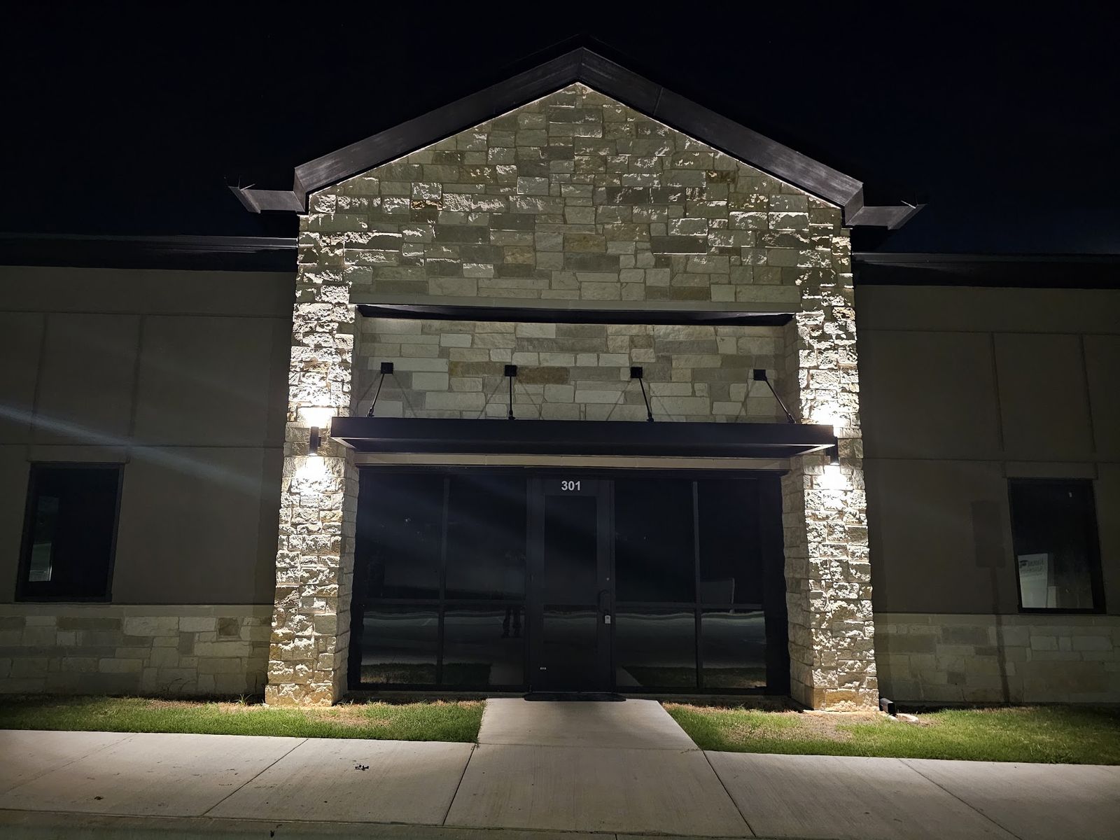 Commercial building entrance lit at night by exterior wall lighting