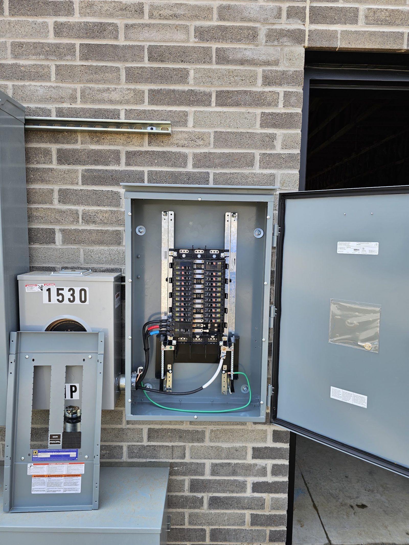 Commercial panel and service disconnect mounted on a brick exterior wall with conduit