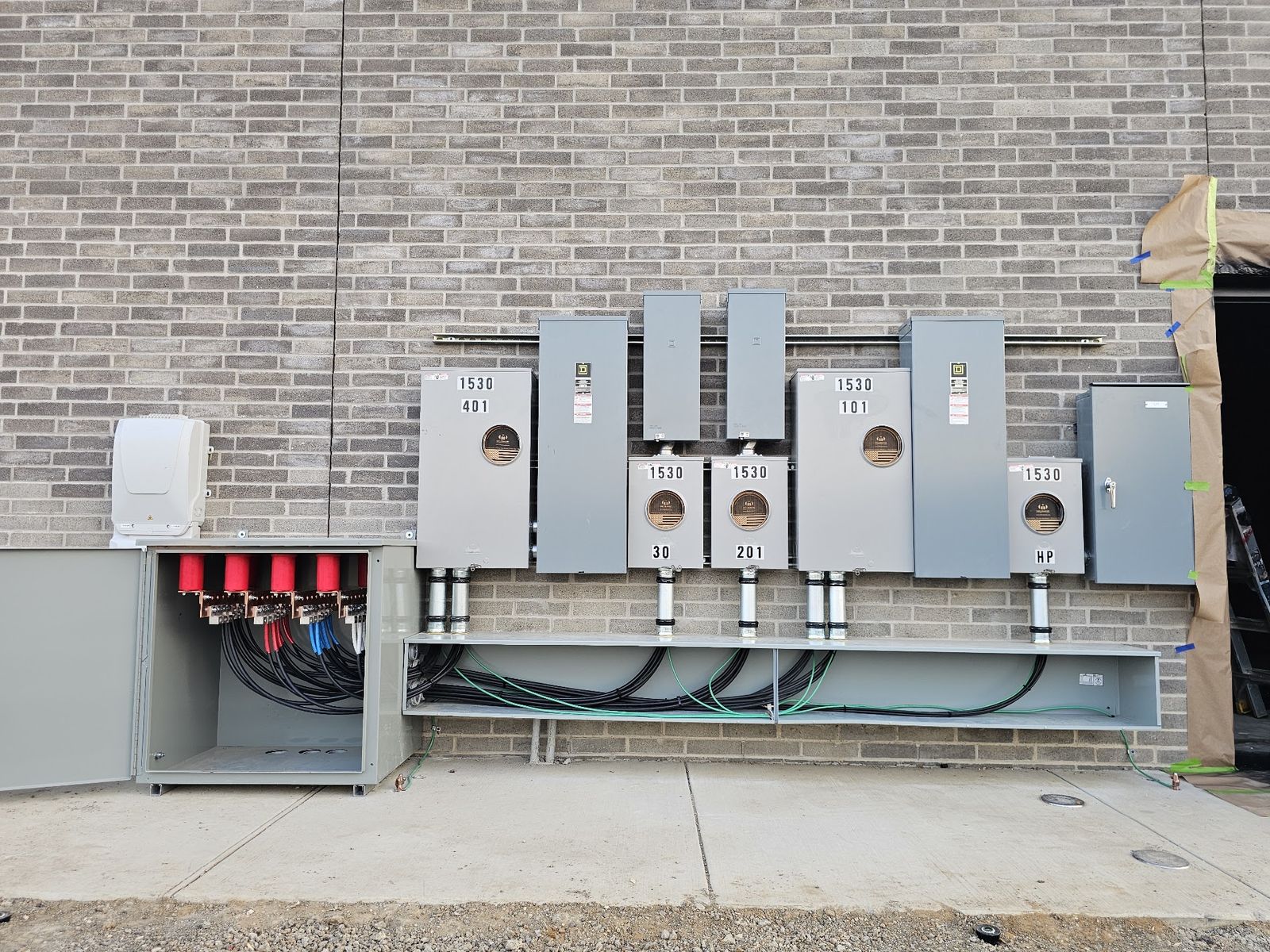 Bank of commercial meters, disconnects and distribution equipment mounted on a building exterior