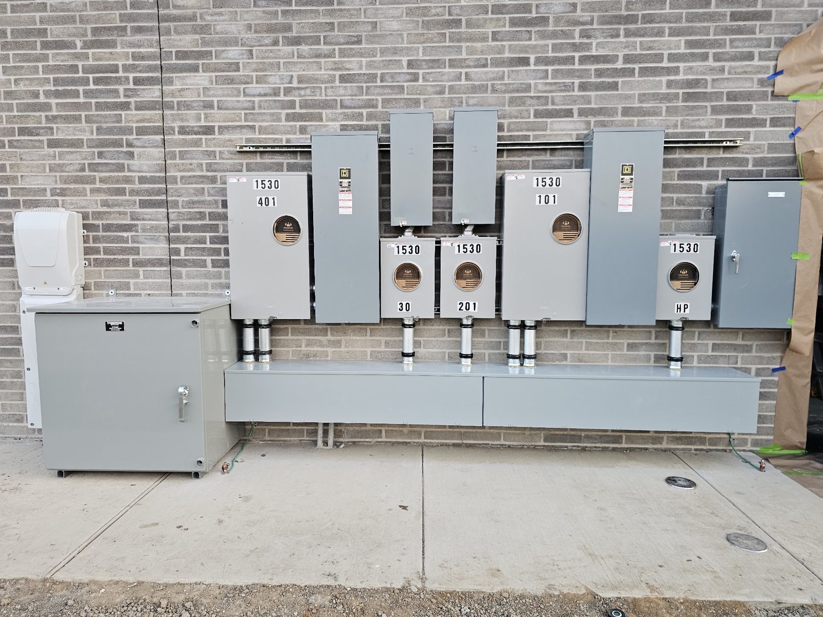 Tenant meter and disconnect assembly mounted on a commercial brick wall