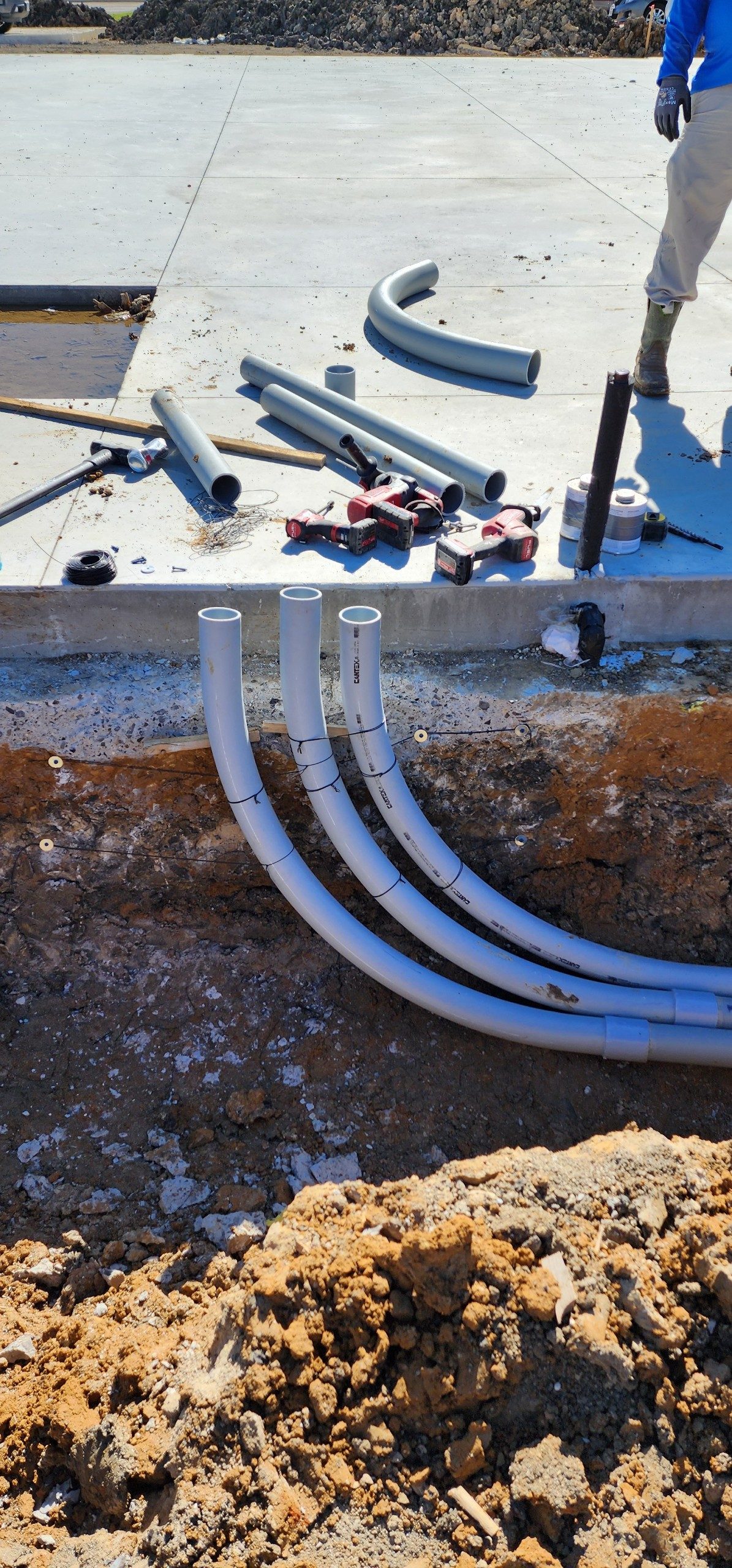 Underground electrical conduit sweeps set in an open trench at a commercial site